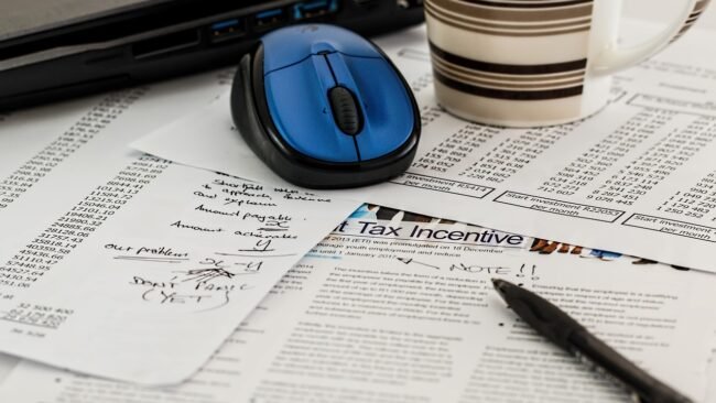 A person calculating website traffic volume with a calculator and notepad
