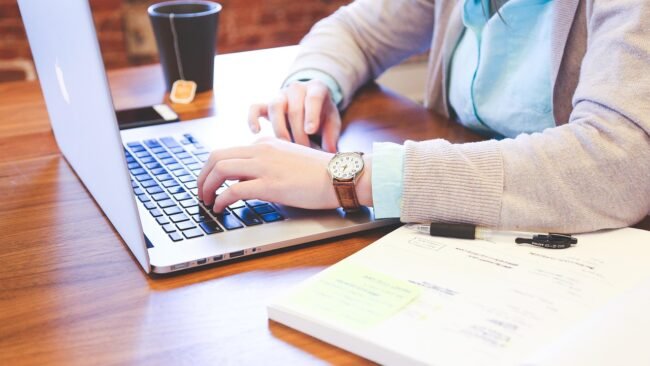 A writer focused on typing content on a laptop in a cozy setting.