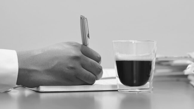 An editor reviewing a manuscript with a red pen in hand.